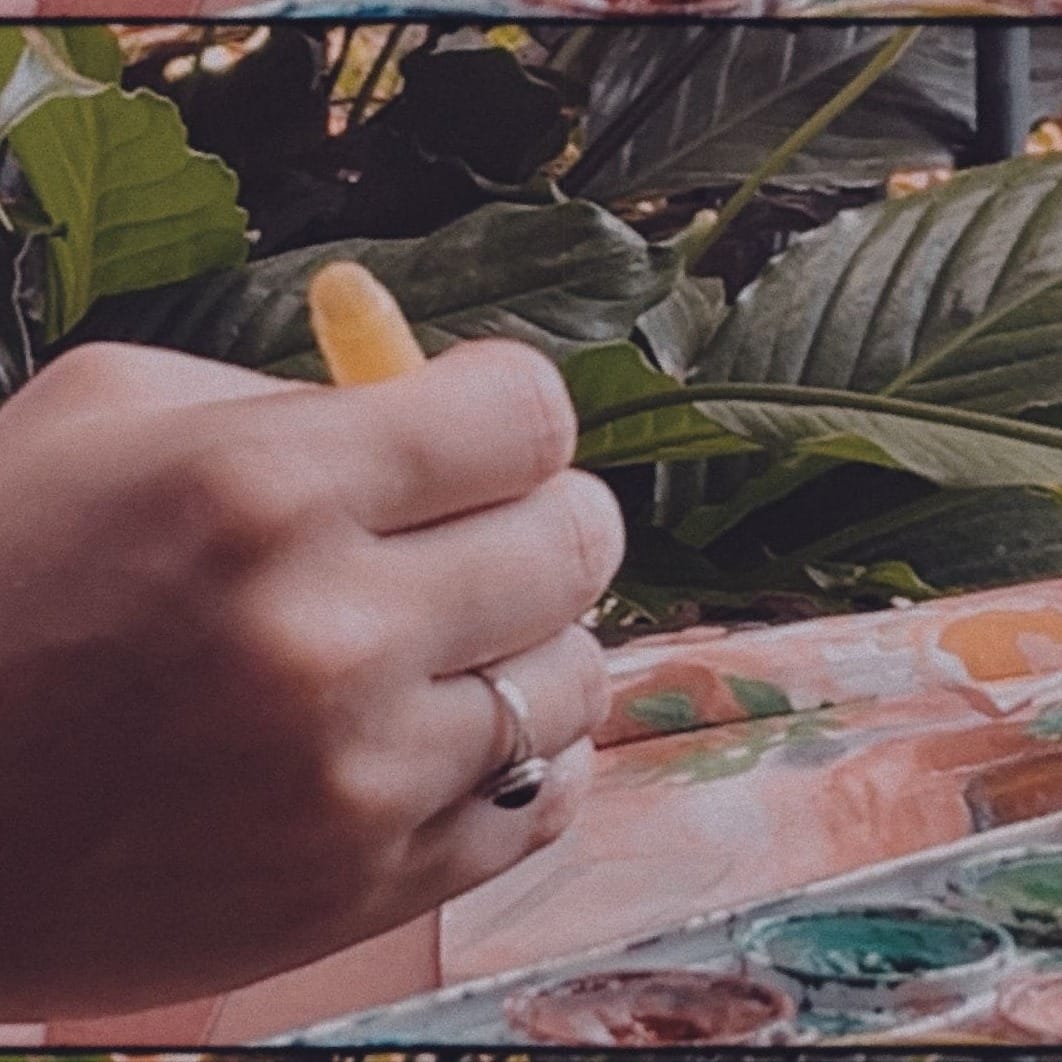 Close up photo of Marianna's hand painting, in film style